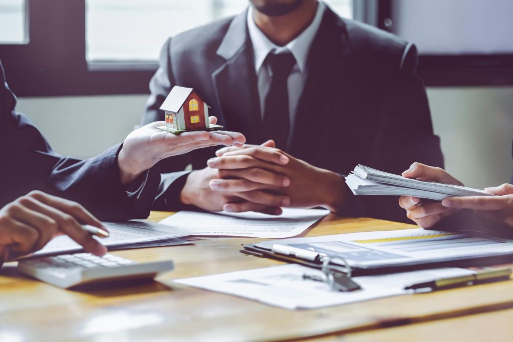 Professionals discussing together with one holding a miniature home