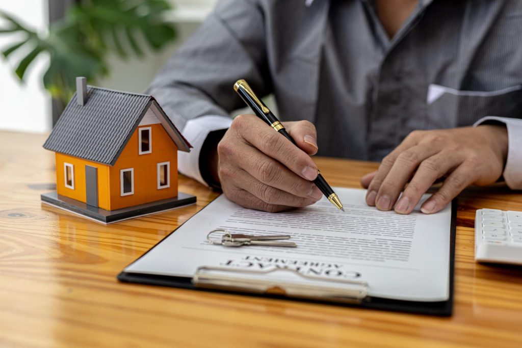 Professional signing contract with miniature house on table