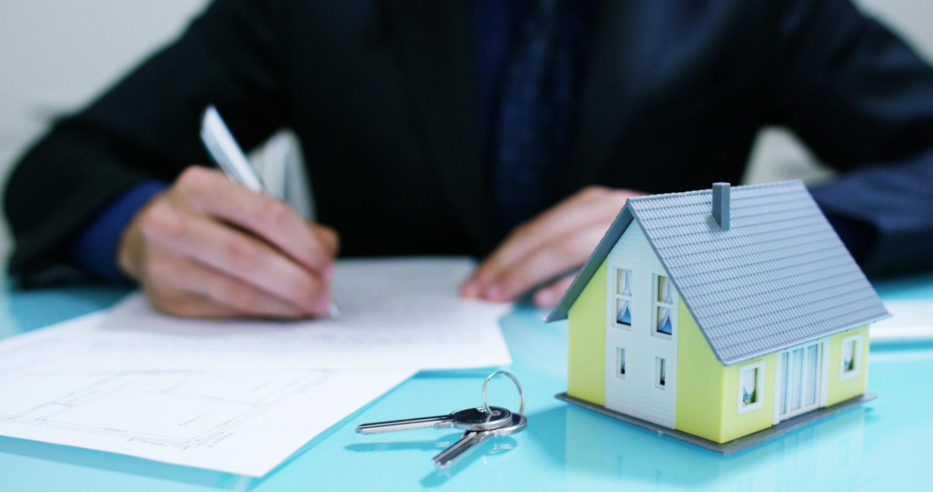 Professional working in the office with miniature house on table