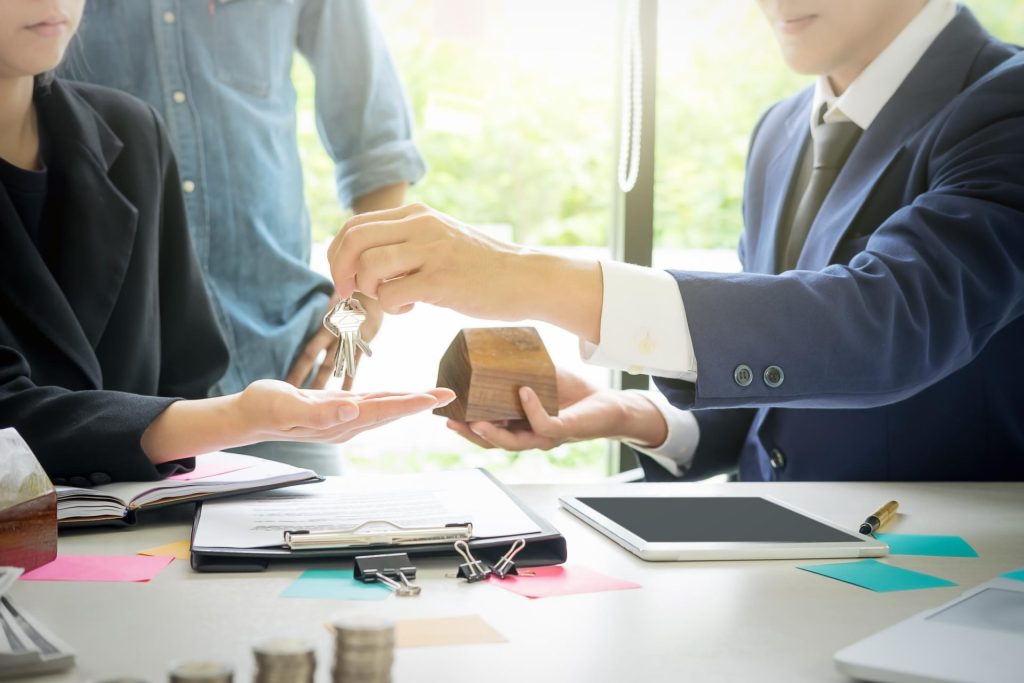 Broker handing house keys to client while signing the deal contract